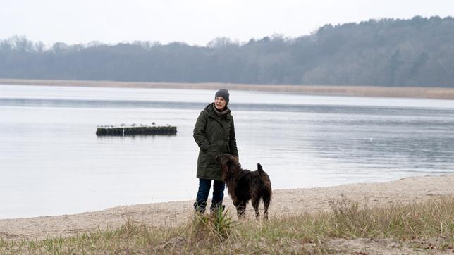 Karin Lossow (Katrin Sass) mit Hund Lucky am Wasser.