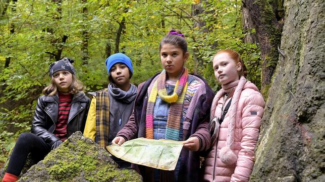 Tilly (Lola du Bled Michels), Sophie (May Fischer), Marla (Eda Jülide Sari) und Lilia (Amy Fürstenfeld) meistern mit Hilfe der Karte den Abenteuer-Parcours. An der Höhle angekommen, Amy Fürstenfeld (Lilia), May Fischer (Sophie), Eda Jülide Sari (Marla), Lola du Bled Michels (Tilly).