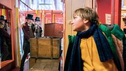 Frido (Luis Vorbach) versteckt sich hinter dem Schrank, während der Spiegelkabinettbesitzer (Butz Buse) eine Kiste verschiebt.