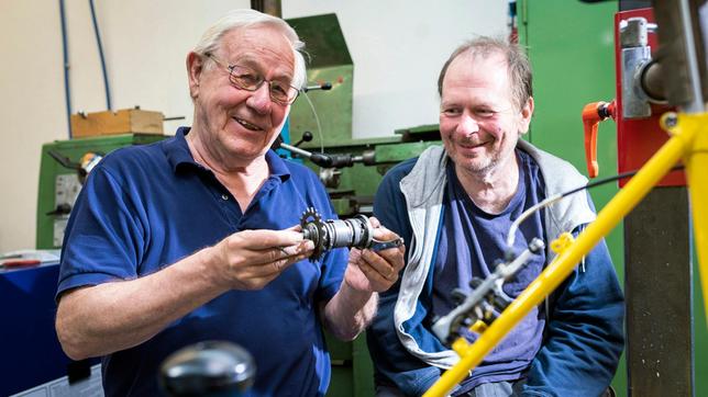 Maus-Filmemacher Armin Maiwald (links) baut mit Hilfe von Dietmar Hertel (rechts) ein Fahrrad.