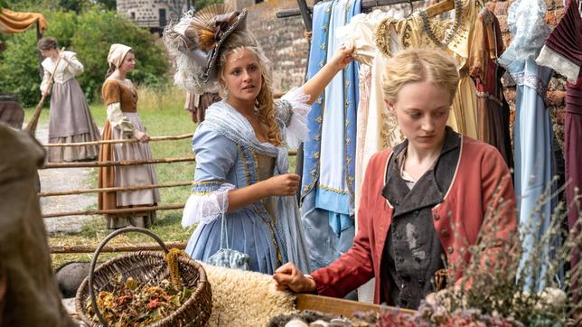 Prinzessin Josefine (Lucie Hollmann) entdeckt auf dem Markt die schönen Kleider von Helene (Caroline Hellwig).