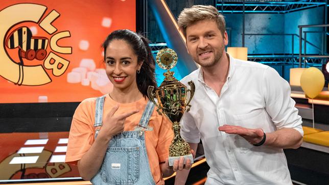 Noch hält das Moderatoren-Duo Muschda Sherzada und Johannes Zenglein den goldenen Tigerenten-Pokal in ihren Händen. Welches Team wird ihn wohl im fairen Wettkampf erspielen – die Frösche oder die Tigerenten?