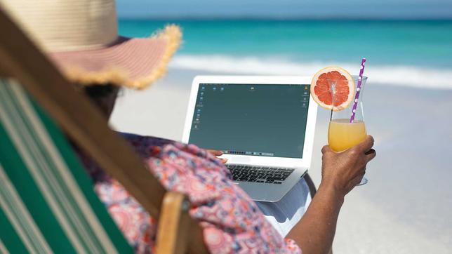 Frau am Strand mit Laptop