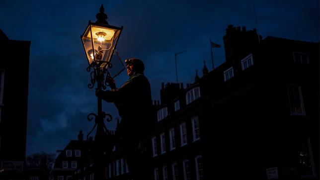 Ein Lampenwärter zündet eine Gaslaterne in London an.