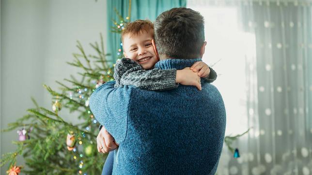 Vater mit Kind vor Weihnachtsbaum