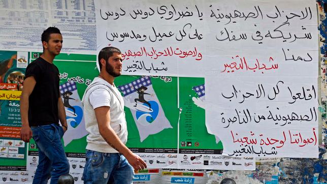 Zwei Männer vor Plakaten mit arabischer Schrift