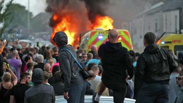 Demonstranten und brennendes Polizeiauto 