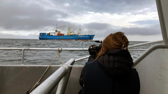 Ein Frau fotografiert von einem Schiff aus ein anderes Schiff