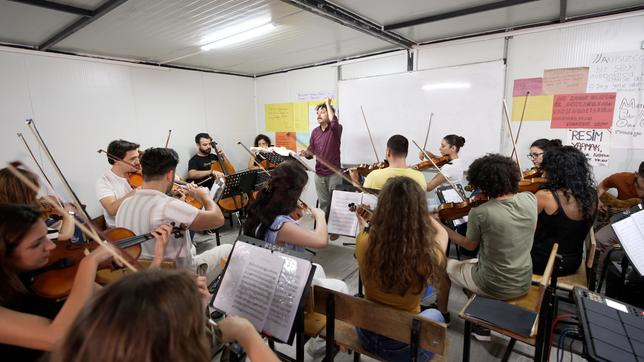 Musiker und Musikerinnen proben mit ihren Instrumenten in einem Containerraum