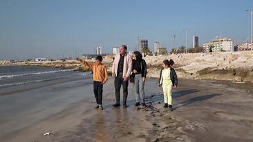 Familie spaziert an Strand entlang 