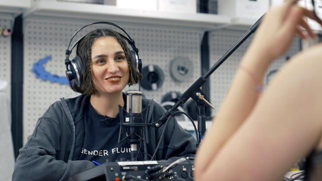 Eine Frau vor einem Mikrofon beim Aufnehmen eines Podcasts