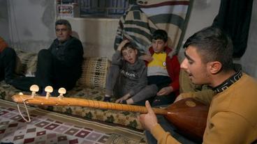 Eine Familie sitzt auf dem Boden und singt.