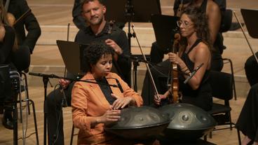 Eine Schwarze Musikerin spielt auf einem im klassischen Orchester selten zu hörenden Handpan.