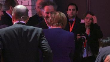 Eine Menschengruppe. Darin Alex Karp und Angela Merkel.