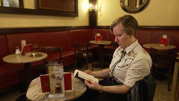 Die österreichische Schriftstellerin Raphaela Edelbauer sitzt in einem Cafe und liest.