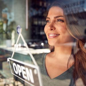 Frau hinter Fenster mit "open"-Schild