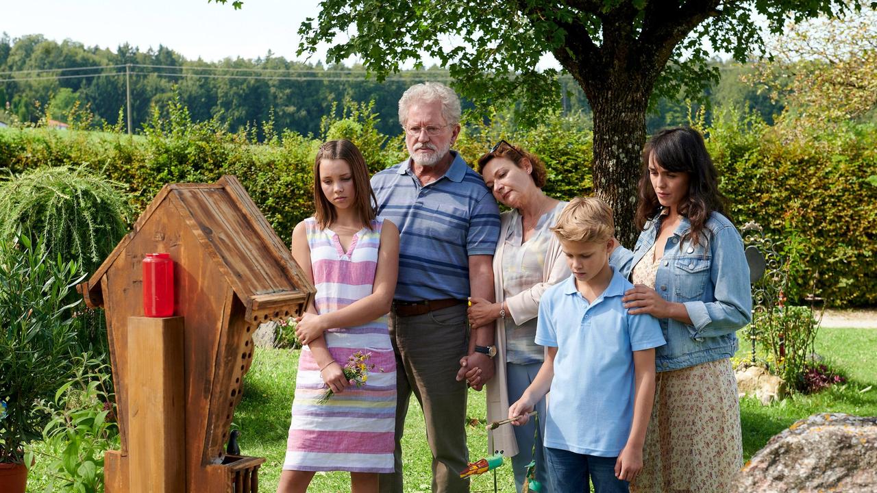 Julika (Lucie Heinze, re.) trauert mit ihren Kindern Leni (Falka Klare, li.), Max (Simon Tiefenbacher, 2. v. re.) und ihren Schwiegereltern Georg (Miroslav Nemec, 2. v. li.) und Christa (Lilly Forgách, 3. v. li.).