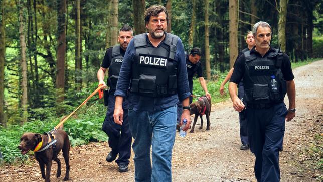 Friedemann Berg (Hans-Jochen Wagner) ist mit der Hundestaffel auf der Suche, in der Hoffnung, die geflüchteten Verdächtigen so schnell wie möglich zu stellen.