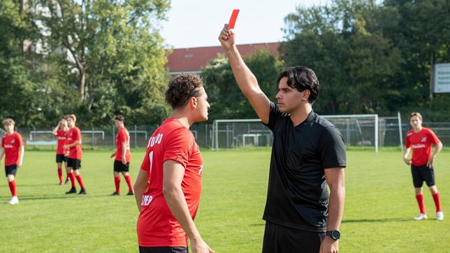 Schiedsrichter Fahri Oktay (Skandar Amini) zeigt Matthias Kemper (Samy Abdel Fattah) die rote Karte - und schmeißt damit seinen Halbbruder aus dem Spiel (mit Komparsen).