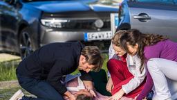 Tessa Schneider (Nell Pietrzyk, liegend) bricht auf dem Parkplatz vor ihrem Mann Dominik (Merlin Leonhardt) zusammen, der sie gegen den ärztlichen Rat von Dr. Elly Winter (Juliane Fisch, 2.v.r. mit Leslie-Vanessa Lill) mit nach Hause nehmen wollte.