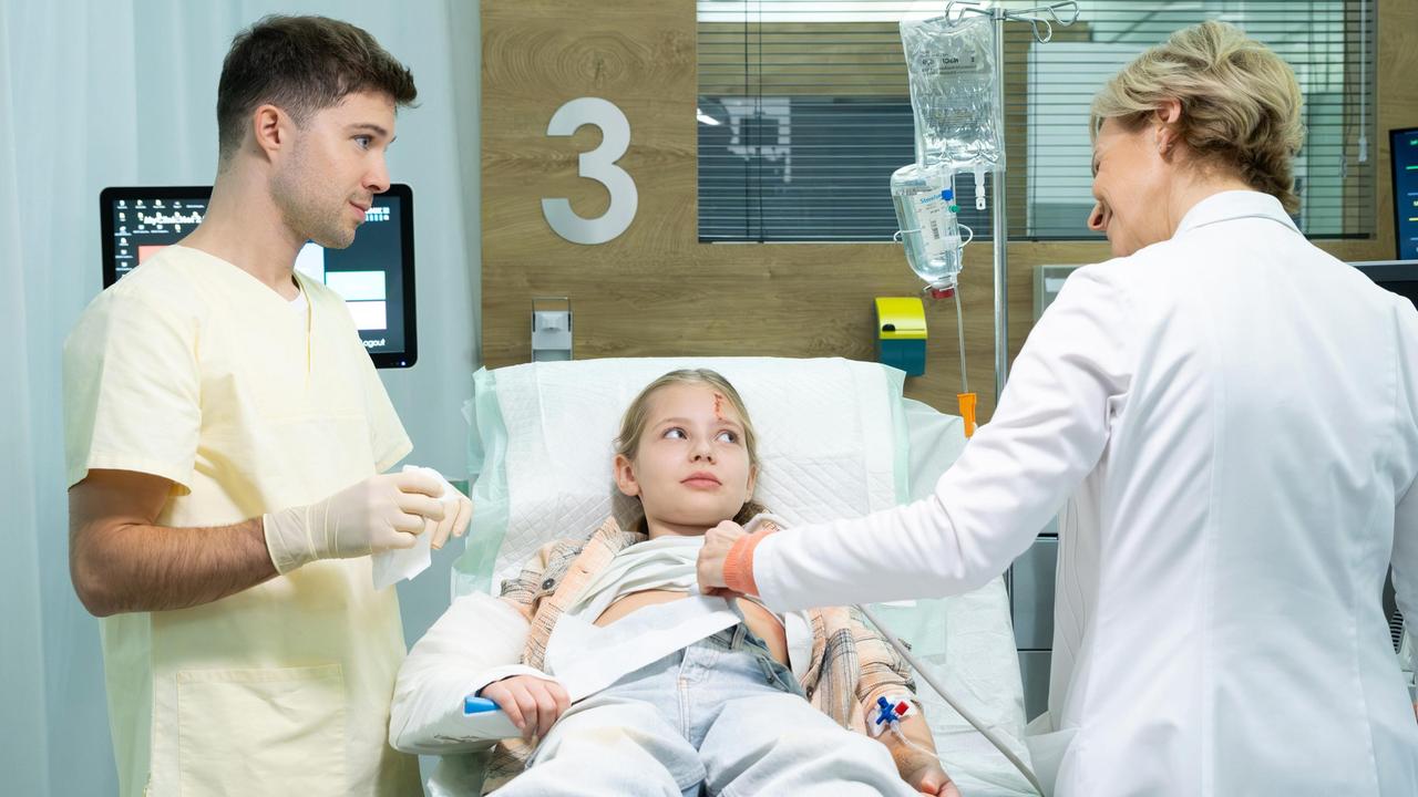 Die neunjährige Olivia Staiger (Elsa Gluth, mi.) wurde mit einem offenen Unterarmbruch von ihrem Vater in die Sachsenklinik gebracht. Sowohl Dr. Kathrin Globisch (Andrea Kathrin Loewig, re.) als auch Kris Haas (Jascha Rust, li.) sind erstaunt, wie tapfer Olivia bei der Untersuchung ist.