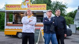 Hans Zielonka (Michael Hanemann), Pastor Puttermann (Johannes Rotter) und Hubert (Matthias Komm) stehen vor Huberts Hähnchenwagen und schauen zum "Pascha Grill", wo die Hindus ihren Gottesdienst feiern.