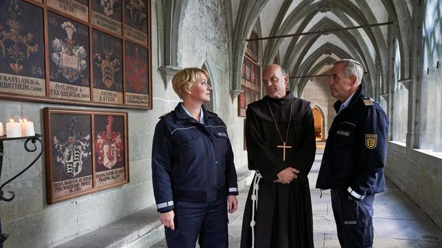 Paul Schott (Tim Wilde) und Nele Fehrenbach (Floriane Daniel) treffen Abt Barnabas (Ulrich Gebauer) im Kreuzgang von Kloster Oberzell.