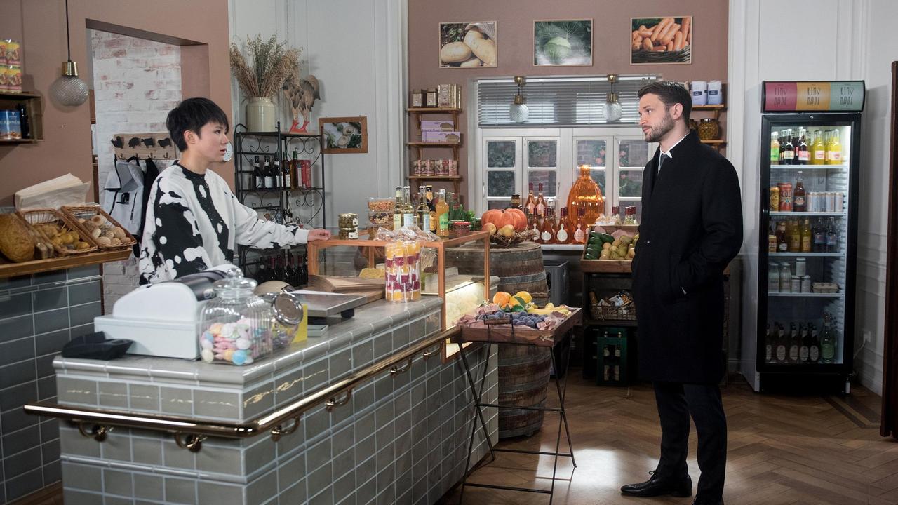 David (Arne Rudolf) kommt in den Gemüseladen, um Ellen (Yun Huang) zu bitten, ihm gegen Amelie beizustehen.