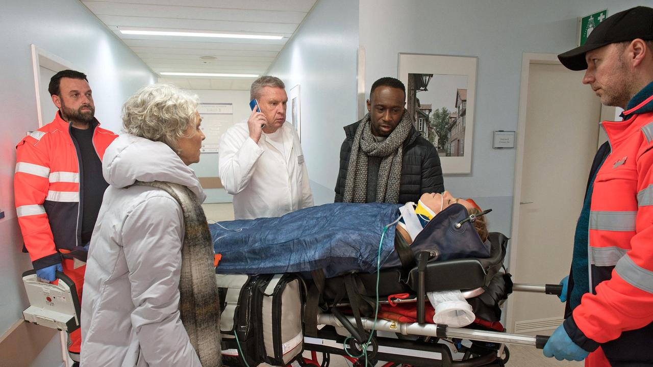 Hendrik (Jerry Kwarteng) ist zur Stelle, als Britta (Jelena Mitschke) ins Krankenhaus eingeliefert wird. Dörte (Edelgard Hansen) erfährt erschrocken, dass Merle Britta angefahren hat (mit Komparsen).
