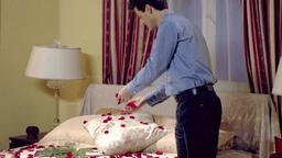 Lars streut rote Rosen aufs Bett