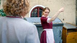 Während Lucy (Jennifer Siemann) Bela (Franz-Xaver Zeller) bei den Vorbereitungen für sein Vorstellungsgespräch hilft, findet sie ein Amulett im Müll.