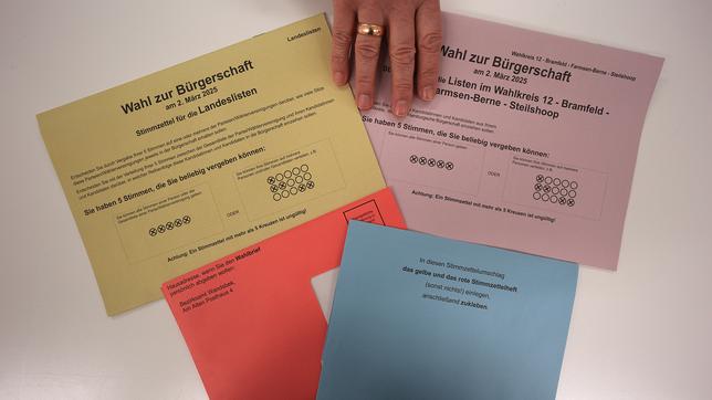 Ein Wahlhelfer legt Stimmzettel und Umschläge für einen Pressetermin auf einen Tisch in der zentralen Briefwahlstelle zur Bürgerschaftswahl und Bundestagswahl 2025 auf dem Gerhart-Hauptmann-Platz. 